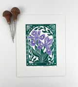 A block print of purple flowers with green leave and ornate details. 