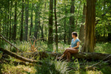 Katie Hayes sitting on a log in a forest