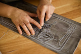 Hands working on a black and white design on a wooden surface