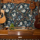 Dark floral pattern with cream magnolias, blue berries, green leaves and brown branches on black bac