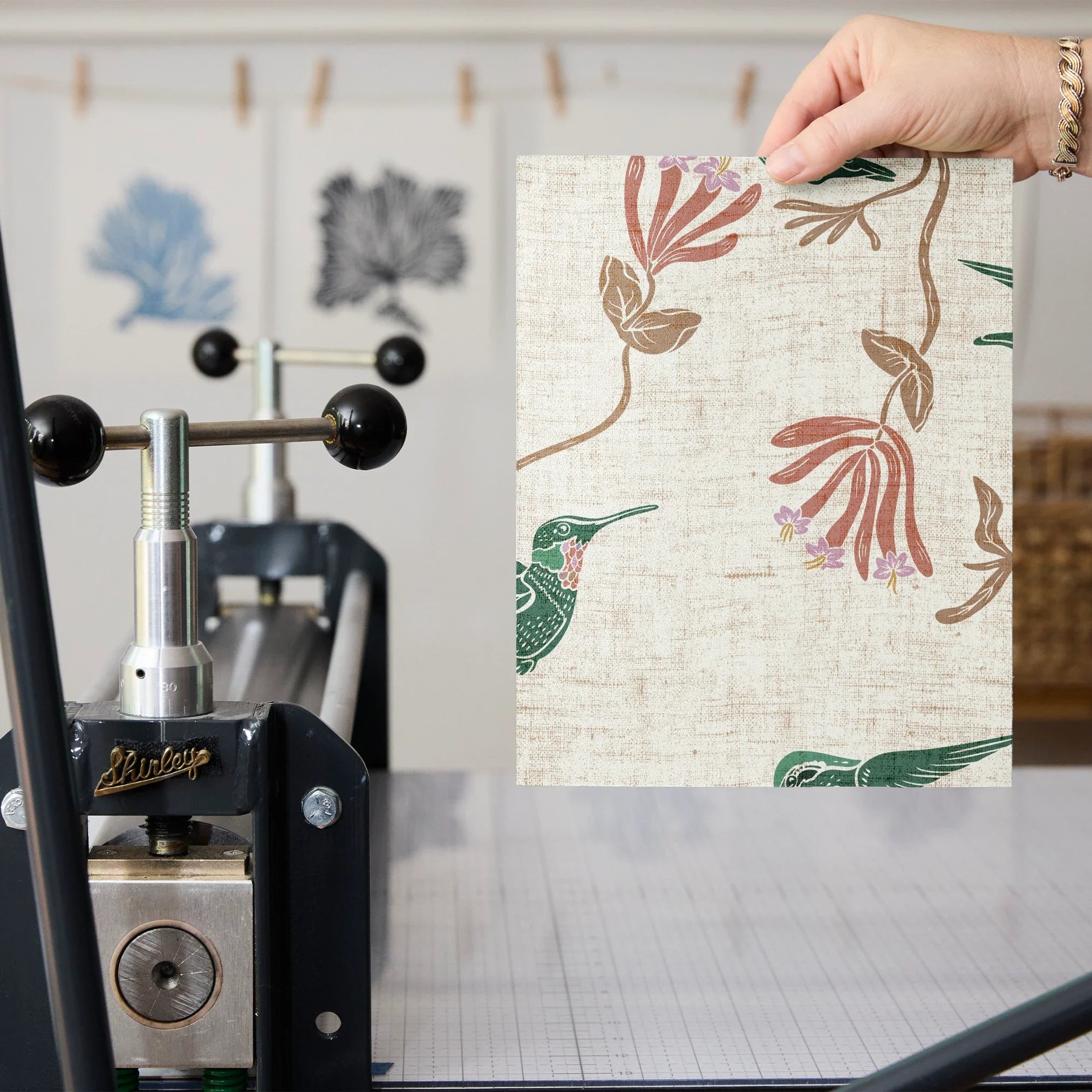 Floral pattern with hummingbirds, pink flowers, and tan foliage on cream textured background