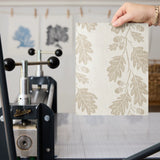 Beige oak leaf pattern on cream textured background with acorns and branches