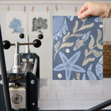 Symmetrical decorative pattern with crabs, starfish, and seashells in blue and gold tones