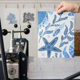 Symmetrical blue and white maritime pattern with starfish, crabs, shells, and fish motifs