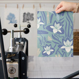 Art Nouveau floral pattern with white lilies, blue-green leaves and decorative pods on blue backgrou
