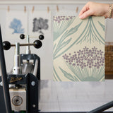 Art Nouveau wallpaper pattern with stylized flowers in purple and teal on beige background