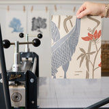 Decorative pattern with blue herons, beige cranes, and red flowers on cream background