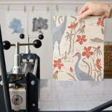 Herons and cranes among red flowers and beige foliage in Asian-inspired decorative pattern