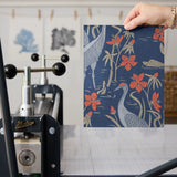 Blue wallpaper pattern with white herons, coral flowers, and green foliage in an Art Nouveau style