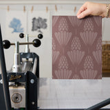 Art deco style pattern with stylized pinecones and fan shapes in muted rose and mauve tones