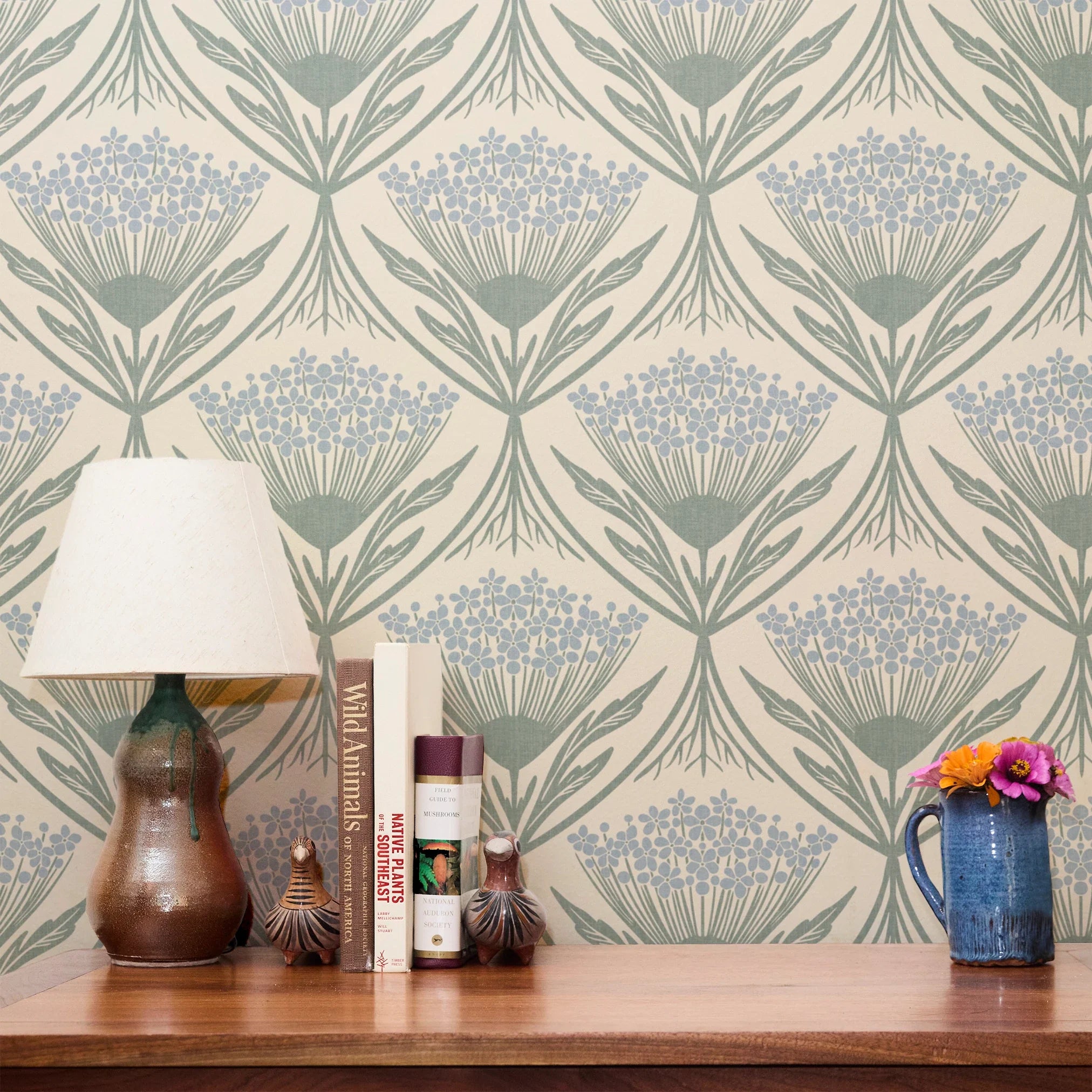 Art Nouveau floral pattern with stylized blue flowers and sage green leaves on cream background