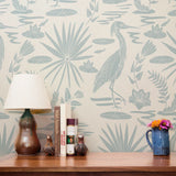 Tropical pattern with herons, palm fronds, and foliage in sage green on cream background