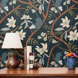Dark floral pattern with cream magnolias, blue berries, green leaves and brown branches on black bac