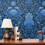 Symmetrical blue folk art design with hands forming heart shape, surrounded by botanical motifs
