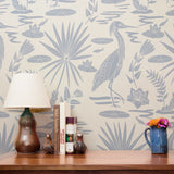 Tropical pattern with palm fronds, herons, and foliage in soft blue-gray on cream background