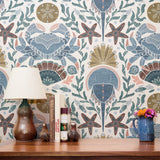 Symmetrical coastal pattern with crab, starfish, seashells, and seaweed in blue, brown, and pink ton
