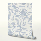 Tropical pattern with palm fronds, herons, and foliage in soft blue-gray on cream background